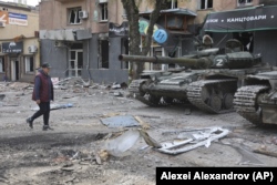 Жительница Мариуполя и военная техника так называемой "ДНР" на улице в Мариуполе. 4 мая 2022 года. Фото: AP